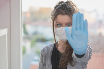 Fototapeta na wymiar woman in protective mask and wearing surgical gloves doing stop gesture sign