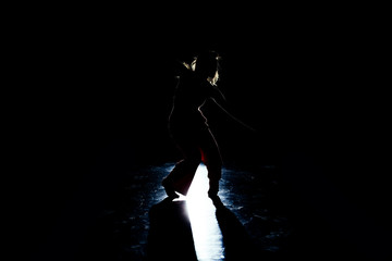 Modern female dancer practicing against black wall