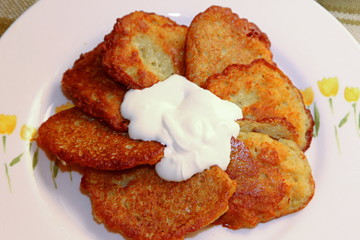 Homemade traditional potato pancakes, served with sour cream, top view.