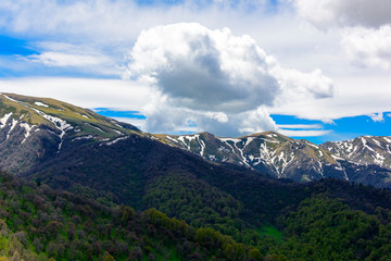 Beautiful mountain panorama with lush greens, blue skies, and puffy clouds