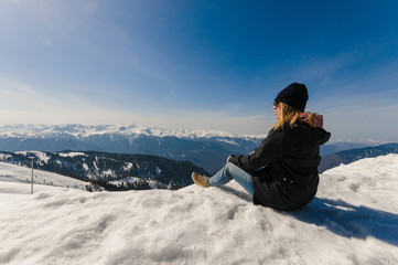 Fototapeta na wymiar Girl sits on top of a mountain in winter