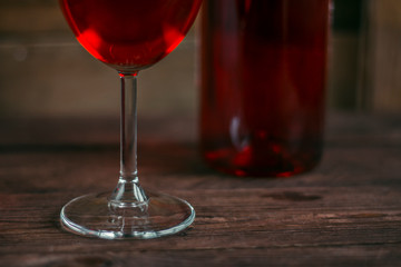 Red wine in a glass goblet on wooden background. Alcoholic drinks. The leg of a glass close-up.