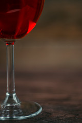 Red wine in a glass goblet on wooden background. Alcoholic drinks. The leg of a glass close-up.