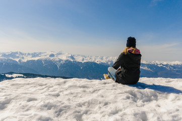Fototapeta na wymiar Girl sits on top of a mountain in winter