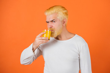 Fototapeta premium Man with orange hair drinking fresh orange juice Concept of healthy food and lifestyle. Young man with glass of orange juice.