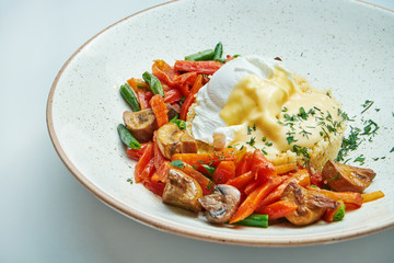 Dietary and healthy food porridge couscous with boiled vegetables (carrots, asparagus, mushrooms) and poached egg in cheese sauce in a gray plate isolated on grey