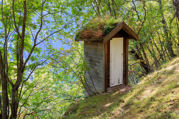 Fototapeta na wymiar GEIRANGER, NORWAY - 2017 SEPTEMBER 03. Small outside toilet house in the mountain of Geiranger . Used for old days and even today close to Seven Sister waterfall in Geiranger with 250 m fall.