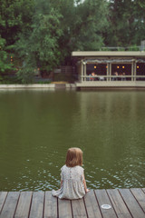 little girl sitting on a wooden bridge