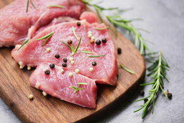 Raw pork meat on wooden cutting board on the kitchen table for cooking pork steak roasted or grilled with ingredients herb and spices Fresh pork