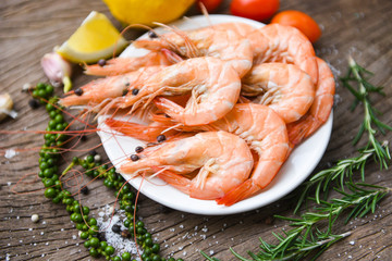 fresh shrimp on white plate with ingredients herb and spices / cooking seafood shrimps prawns served on a wooden table background