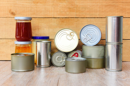 Various canned food in metal cans on wooden background - canned goods non perishable food storage goods in kitchen home or for donations