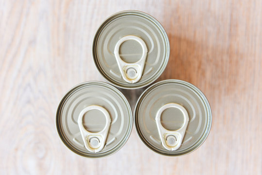 Canned food in metal cans on wooden background , top view - canned goods non perishable food storage goods in kitchen home or for donations