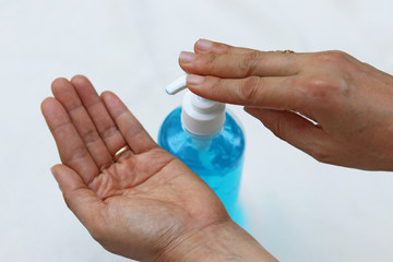 Female fingers pumping alcohol-based hand sanitizer gel on hand for killing germs, bacteria and virus. Disinfection concept of cleaning and washing hands with alcohol sanitizer.