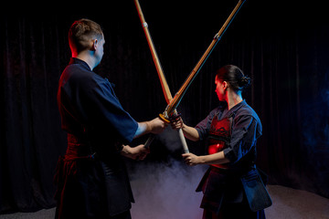 Fototapeta na wymiar two kendo fighters opposite each other with shinai isolated over dark space. Japanese martial art of sword fighting. kendo concept. teacher or trainer and pupil