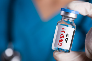 Female doctor with a stethoscope on shoulder holding syringe and COVID-19 vaccine. Healthcare And Medical concept.