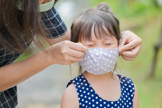 Mother is wearing a cloth mask for little girl protect herself from Coronavirus when child leave house to public area mom is wearing mask on nose for safety outdoor activity,illness or Air pollution