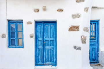 Fototapeta premium The facade of an old traditional house with deep blue wooden door and window in Serifos island Cyclades Greece