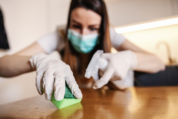 Woman cleaning table with antibacterial wipe and sanitizing agent for viruses on home surfaces....