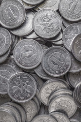 Field of Japanese coins at 1 yen close-up. Dark background or wallpaper with aged effect. News about the economy, finance and interest rate of the central bank of Japan. Vertical shot. Macro