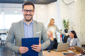 Smiling businessman holding folder in office