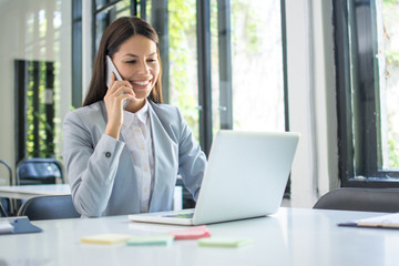 Businesswoman talking on the phone while working on laptop in office. Business concept.