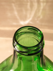 Bottleneck of green bottle in close up, with defocused light background