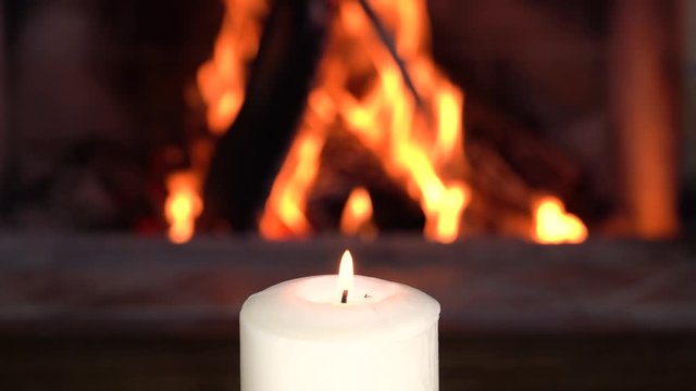 Candle against Cozy fireplace in country house, winter.