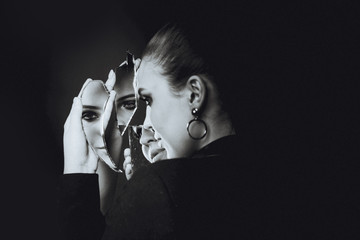 Beautiful brunette woman and broken self-image mirror on black - obrazy, fototapety, plakaty