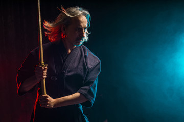 confident strong mature kendo warrior with shinai in hands, preparing for kendo competitions, fighting. isolated smoky space