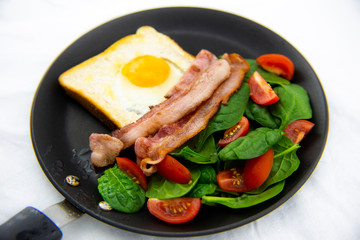 Egg in a hole bread and bacon with salad