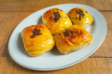 Bolen pisang or banana cake is baked pastry with banana and chocolate filling. In white plate on wooden background
