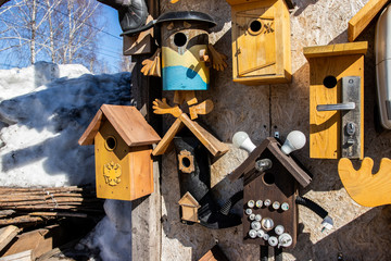 Many different shapes bird feeders birdhouse for nesting box hanging on wooden fence. Bird feeders in park. Colorful bird feeders in rustic garden. Lot of nesting boxes or houses for feeding animals