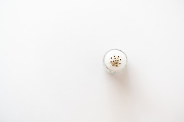 On a white background spice (pepper) in a glass container