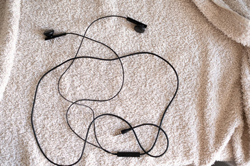 Wired headphones lie on a white background (towel)