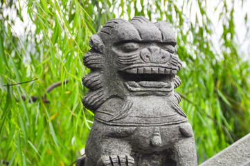 Fototapeta premium Dragon head statue at a bridgte is facing with fog in the background. Selected Focus on dragon head. Background is foliage.