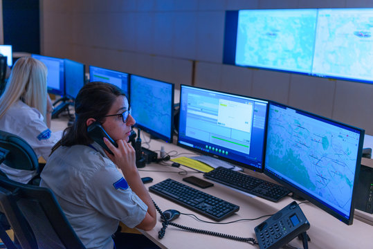 Technical Operator Works At His Workstation With Multiple Displays While Talking On The Phone, Security Guards Working On Multiple Monitors...