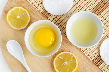 Raw egg in the small white bowl,  lemon juice and slices. Natural homemade hair treatment and zero waste concept. Top view, copy space