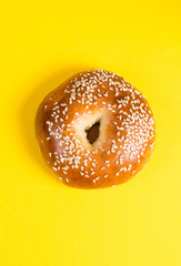 Homemade bagels with sesame seeds on a bright yellow background