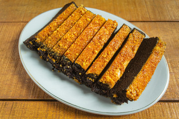 Kue bolu kacang or bolu cake made from flour, chocolate, beans and other ingredients, has a sweet taste. in white plate on wooden background