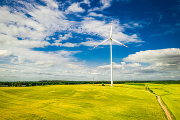 Flying above big wind turbine on rape field
