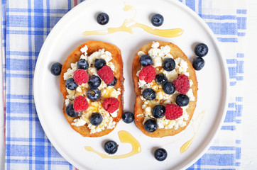 Sandwiches with curd cheese, blueberries, raspberries and honey