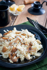 Risotto with chicken and champignons on a black plate, selective focus