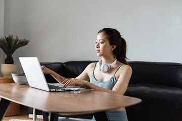 A young Asian woman using a computer in the living room