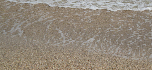 Small waves run onto sandy sea shore