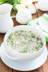 Traditional summer okroshka soup with sausage in a white bowl, selective focus