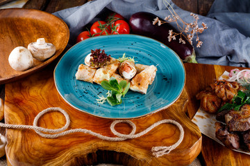 Pancakes with salmon and greenery on a background of blue plates