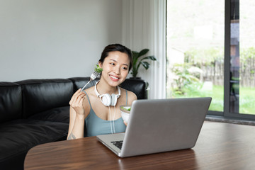 A young Asian woman using a computer in the living room