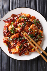 Crispy, tasty chicken pieces stir-fried with a generous amount of dried chillies and Sichuan pepper close-up in a plate. vertical top view
