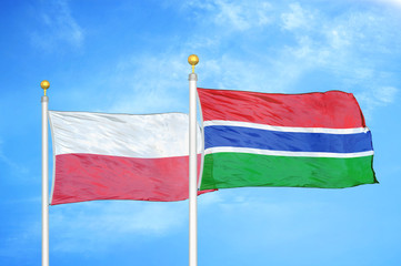 Poland and Gambia two flags on flagpoles and blue cloudy sky