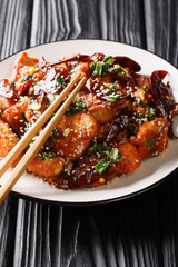 Mala Chicken Spicy Sichuan Chicken with dry chili pepper, sesame seeds and herbs close-up in a plate. vertical